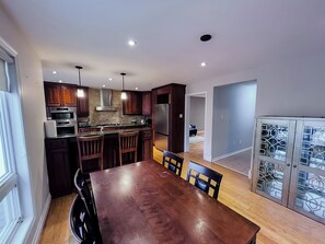 A modern kitchen with dark wooden cabinets, stainless steel appliances, and a central island with bar stools. - Family Comfort Retreat (Brampton)