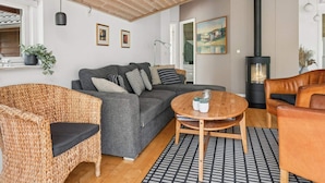 A cozy living room with a sofa, wicker chair, and a round wooden table. - 4 Star Holiday Home in Rodby (Rodby)