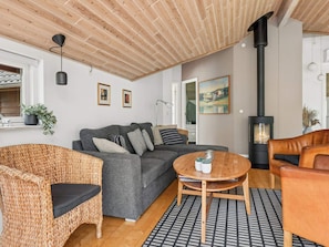 Ein gemütliches Wohnzimmer mit einer Couch, einem Korbsessel und einem runden Holztisch.