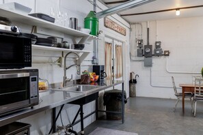 Eine Küche mit Mikrowelle, Spüle und verschiedenen Küchenutensilien in Regalen.
