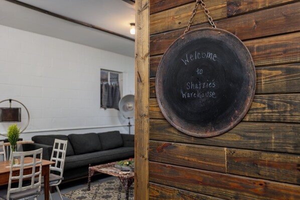 Ein rustikales Interieur mit einer Holzwand, einem Tafelschild, einer Couch und einem Essbereich.