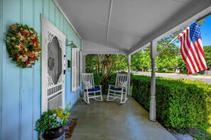 Eine Veranda mit zwei Schaukelstühlen, einem Kranz und einer amerikanischen Flagge.