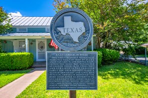 Ein Schild der Texas Historical Commission mit einer Beschreibung des Riley-Enderlin-Hauses, einem Wohnhaus im Volkstil, entworfen und gebaut 1909, mit einem Satteldach, einem Vordach mit Flachdach und zwei einteiligen Eingangstüren.