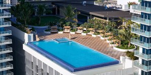 A rooftop pool with a clear view of the surrounding buildings, a landscaped area with palm trees, and a modern architectural design. - Newly Built High-Floor Condo with Diamond head & Ocean Views & Luxury Amenities (Honolulu)
