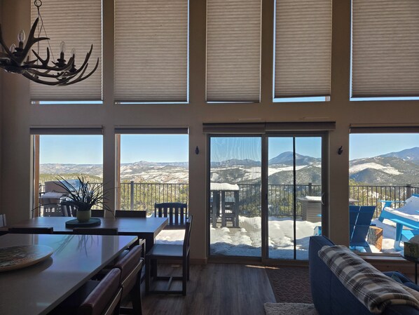A spacious room with a large dining table, a seating area with a sofa, and a view of snow-covered mountains through large windows. - Charming 3-bedroom house in beautiful Bailey perfect for relaxing stays (Bailey)