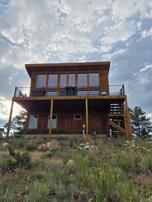 A two-story wooden cabin with a balcony, large windows, and a wooden deck. - Charming 3-bedroom house in beautiful Bailey perfect for relaxing stays (Bailey)