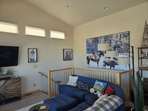 A living room with a blue sofa, a mounted TV, and a large abstract painting. - Charming 3-bedroom house in beautiful Bailey perfect for relaxing stays (Bailey)
