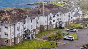 Un edificio residencial con varias unidades, un jardín delantero con césped y vista al mar.