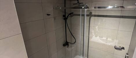 Un baño moderno con ducha envuelta en vidrio, inodoro y lavamanos.