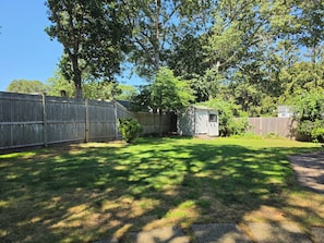 Ein eingezäunter Garten mit einem kleinen Gartenhaus und einem Baum.