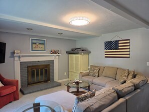 Een woonkamer met een open haard, een bank, een glazen salontafel en een gehangen Amerikaanse vlag.