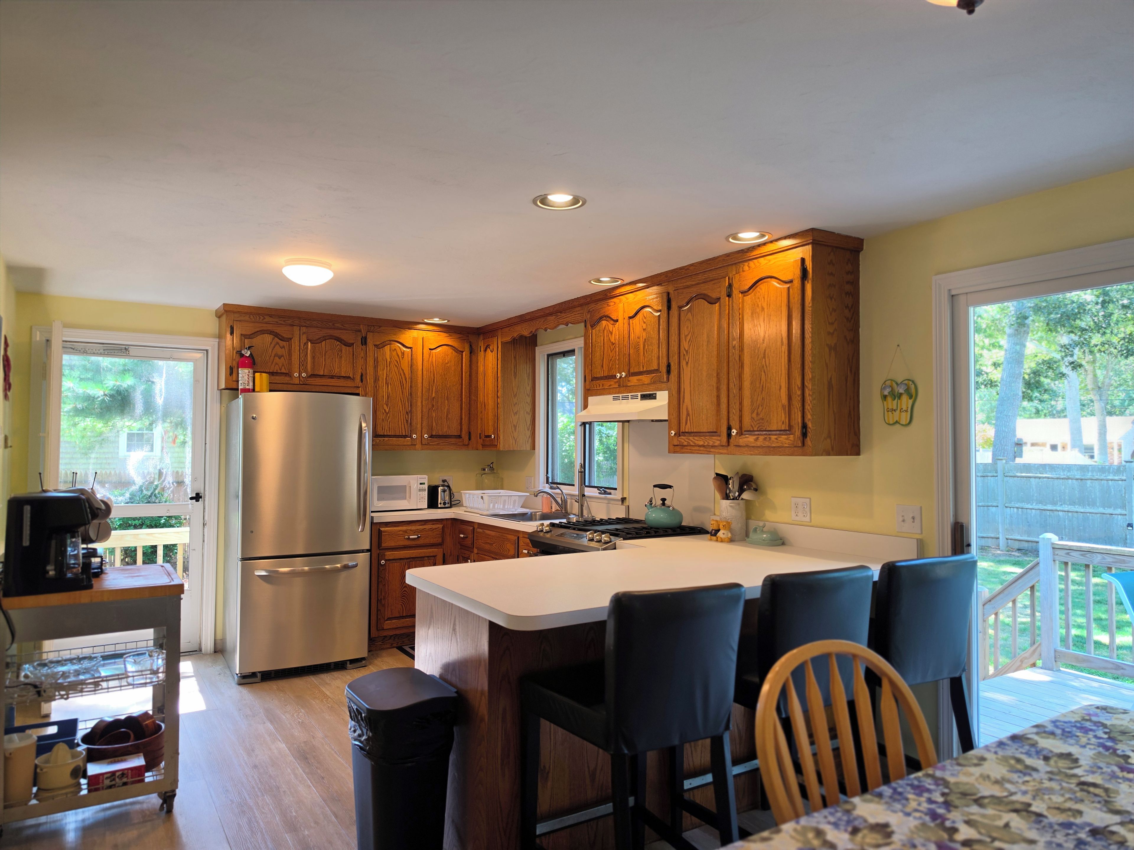 A kitchen with wooden cabinets, a stainless steel refrigerator, a microwave, and a sink.