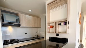 Een moderne keuken met een centraal eiland, zwarte barkrukken en een wijnrek.