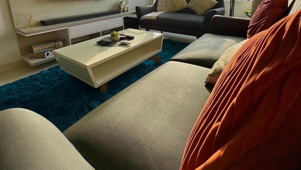 Een moderne woonkamer met een flatscreen televisie, een plafondventilator, een groot raam met uitzicht op de stad, en een gezellige zithoek.