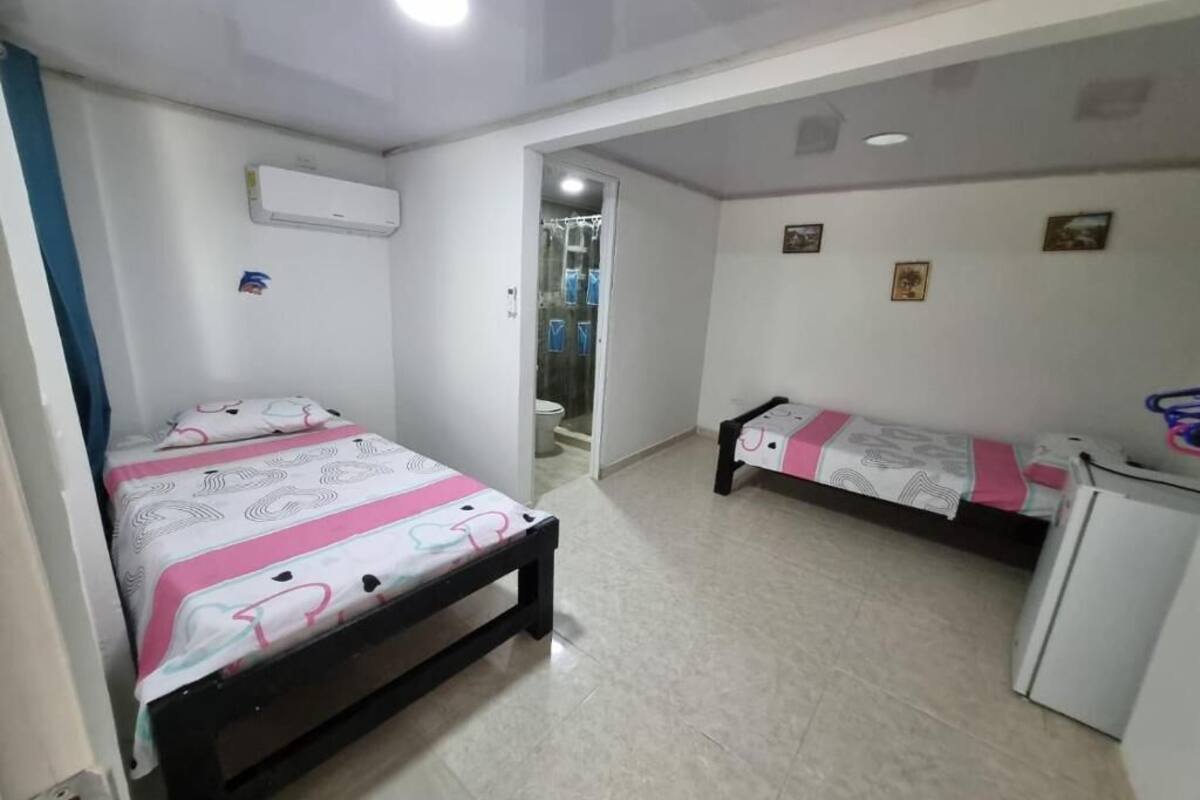 Un dormitorio con dos camas, un escritorio pequeño y un equipo de aire acondicionado.