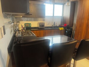 Eine Küche mit einem Gaskochfeld, einem Toaster und einem Fenster.