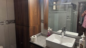 A bathroom with a wooden vanity, a large mirror, a sink, and a shower. - Providencia condo rock star location a block from everything (Guadalajara)