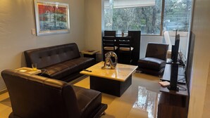 A modern living room with a leather sofa, a coffee table, and a TV stand. - Providencia condo rock star location a block from everything (Guadalajara)