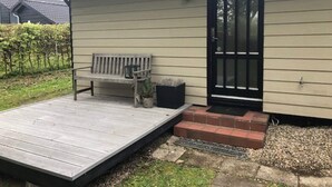 A building with a wooden deck, a bench, a door, and a small garden area. - 4 Star Holiday Home in Esbjerg V (Esbjerg)