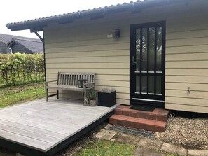 A building with a wooden deck, a bench, a door, and a small garden area. - 4 Star Holiday Home in Esbjerg V (Esbjerg)