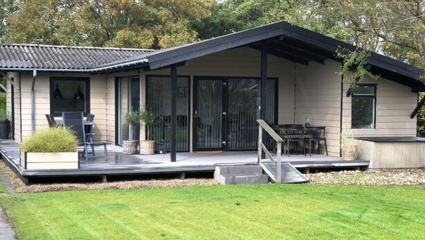 A modern house with a covered patio, outdoor seating, and a well-maintained lawn. - 4 Star Holiday Home in Esbjerg V (Esbjerg)