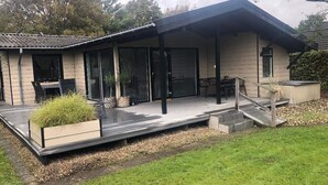 A modern house with a covered patio, a dining area, and a staircase leading to a deck. - 4 Star Holiday Home in Esbjerg V (Esbjerg)