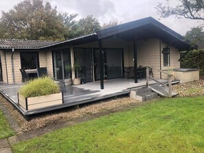 A modern house with a covered patio, a dining area, and a staircase leading to a deck. - 4 Star Holiday Home in Esbjerg V (Esbjerg)