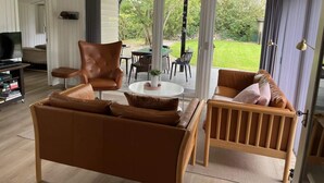 A living room with a sofa, chairs, a TV, and a view of the outdoors. - 4 Star Holiday Home in Esbjerg V (Esbjerg)