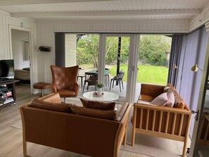 A living room with a sofa, chairs, a TV, and a view of the outdoors. - 4 Star Holiday Home in Esbjerg V (Esbjerg)