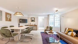 Una sala moderna con comedor, un sofá, una mesa de centro y un televisor.