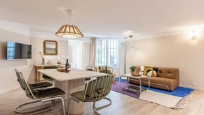 Una sala de estar moderna con comedor, un sofá y un televisor.
