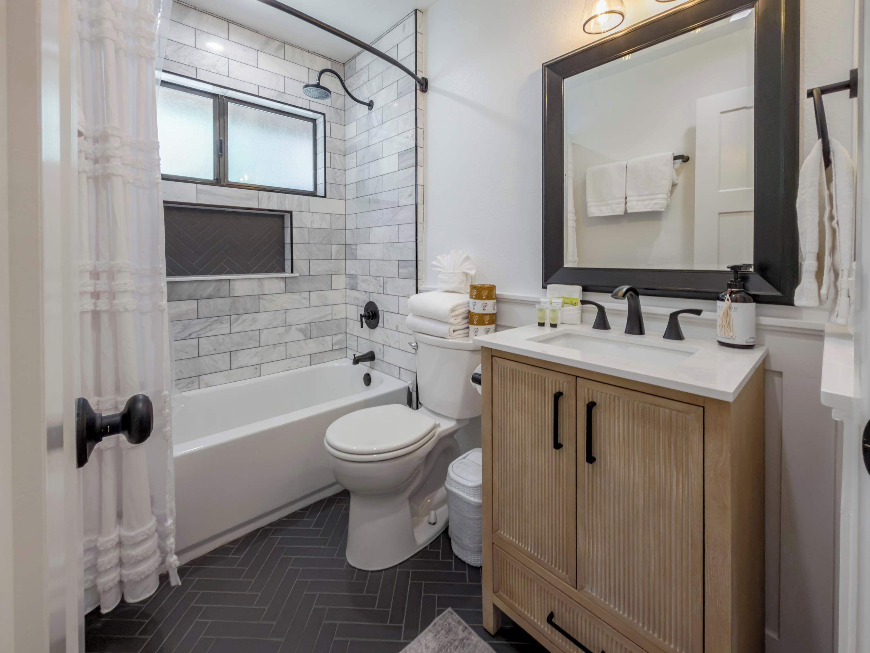 A modern bathroom with a bathtub, toilet, and vanity.