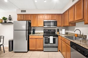 Eine moderne Küche mit Edelstahlgeräten, Holzschränken und einer Arbeitsplatte aus Granit.