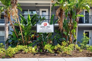A sign for Urban Oasis, a furnished apartment complex, surrounded by tropical plants.