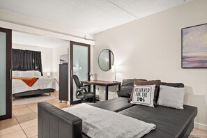 Ein Hotelzimmer mit Bett, Schreibtisch, Sessel, Sofa und Spiegel.