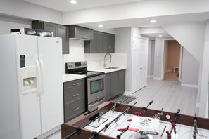 A modern kitchen with grey cabinets, white appliances, and a foosball table.