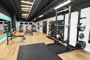 A gym with weightlifting equipment, treadmills, and exercise machines. - Modern 2BR/2BA Corner Suite Near McCormick Place (Chicago)