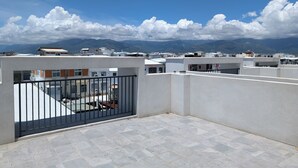 A rooftop terrace with a view of distant mountains, a clear sky, and a tiled floor. - Johnson Bros Inn Taitung (Taitung)