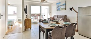 Ein modernes Wohnzimmer mit Essbereich, einer Couch, einem Fernseher und Blick auf die Stadt.