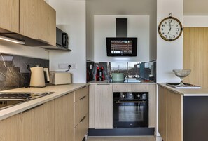 Eine moderne Küche mit Holdekor, Backofen, Mikrowelle und Wandfernseher.