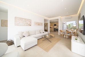 A modern living room with a sofa, coffee table, and dining area. - Casa Luna by BLVE Homes (Yaiza)
