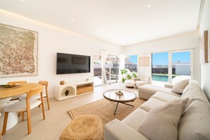 A modern living room with a TV, sofa, and dining area. - Casa Luna by BLVE Homes (Yaiza)