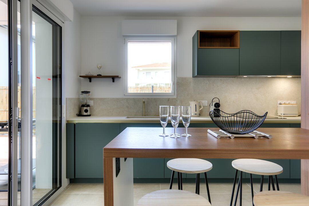 Una cocina moderna con una mesa de madera, dos taburetes y una ventana.