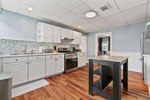 Una cocina moderna con armarios blancos, horno de acero inoxidable y suelo de madera.