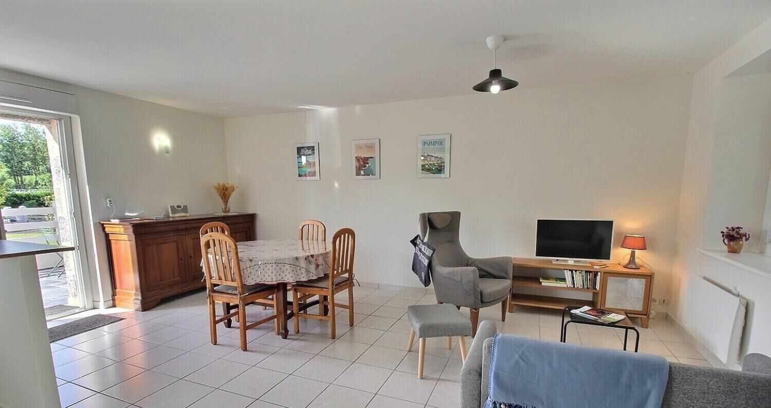 A living room with a dining table, chairs, a sofa, a TV, and a lamp.