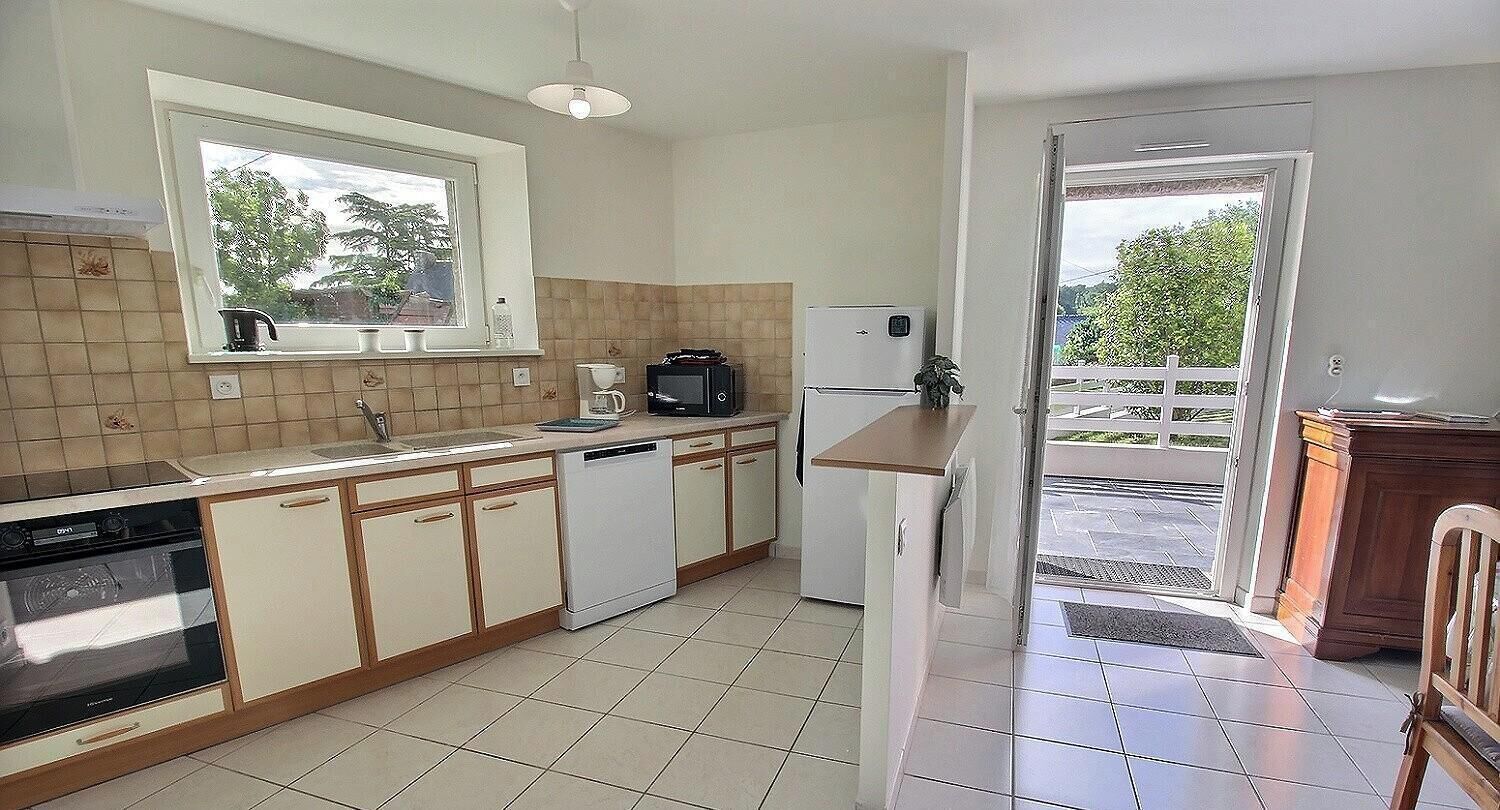 A kitchen with a dishwasher, microwave, and a window overlooking a garden.