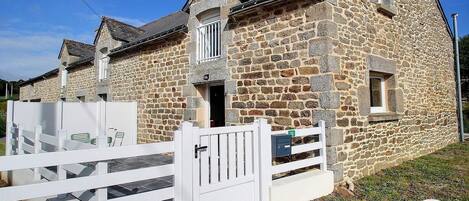 A stone building with a white gate, a small window, and a chimney.