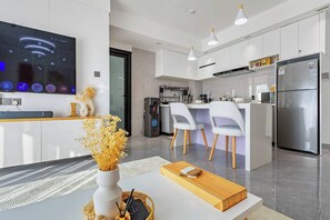 Eine moderne Küche mit integriertem Fernseher, weißen Schränken und einem Edelstahl-Kühlschrank.