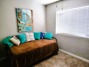 A room with a brown sofa, teal and white pillows, a painting on the wall, and a window with blinds. - El Paso's Premiere Short to Mid Term Rental (El Paso)