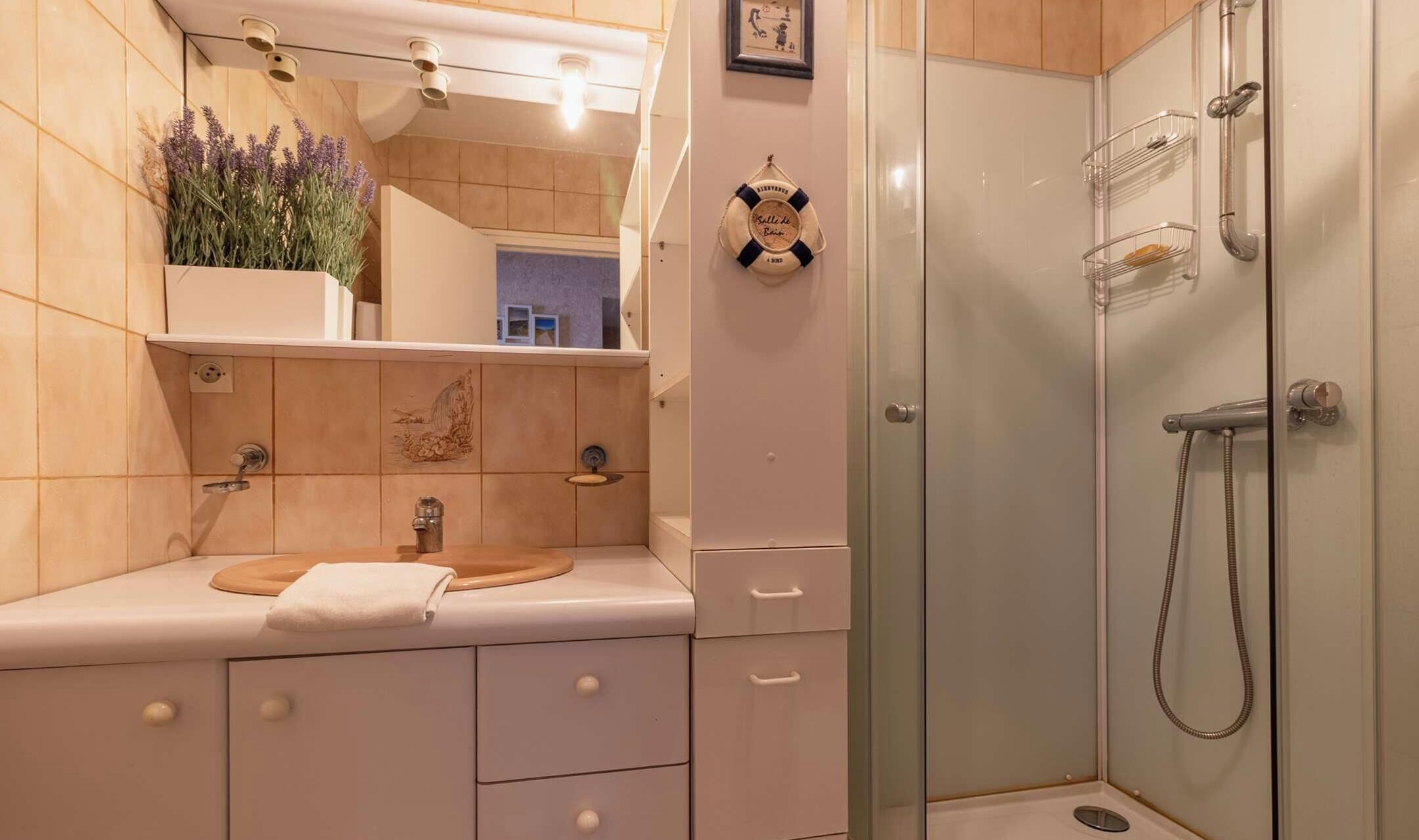 Un baño con ducha, lavabo, toalla y espejo.
